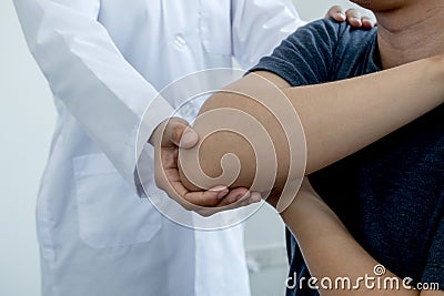 Female physiotherapists provide assistance to male patients with elbow injuries examine patients in rehabilitation centers. Stock Photo