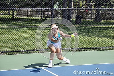 Female pickleball player returns ball at baseline Stock Photo