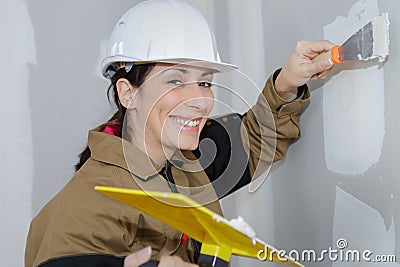 Female plasterer doing wall renovation with spatula and plaster Stock Photo