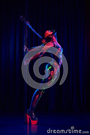 Female pole dancer in bright neon colours under ultraviolet Stock Photo