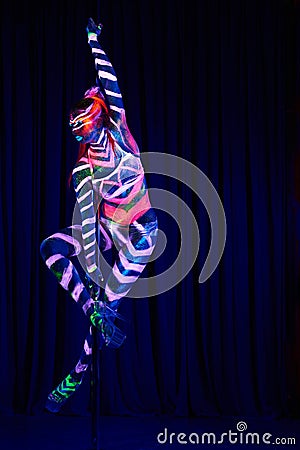 Female pole dancer in bright neon colours under ultraviolet Stock Photo