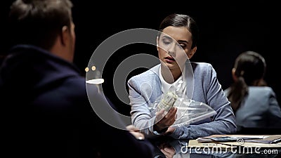 Female police officer showing to criminal cash in physical evidence pack, crime Stock Photo