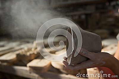 Female potter blowing dust from mud Stock Photo