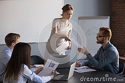 Female presenter giving handout materials to workers Stock Photo