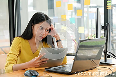 Female programmer are using tablet to create programs for clients. She put hand on temple and face was serious Stock Photo