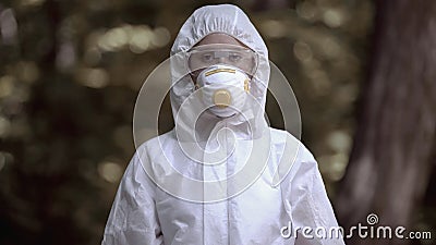 Female in protective mask looking camera, exclusion area research, biohazard Stock Photo