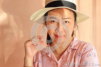 Female protrait in white hat and looking at camera, woman with pink shirt. Stock Photo