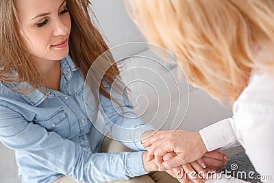 Female psychologyst therapy session with client indoors sitting holding hands close-up Stock Photo