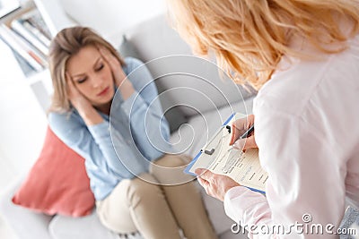 Female psychologyst therapy session with client indoors sitting writing diagnosis Stock Photo