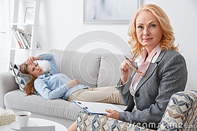 Female psychologyst therapy session with client lying on the sofa indoors looking camera Stock Photo