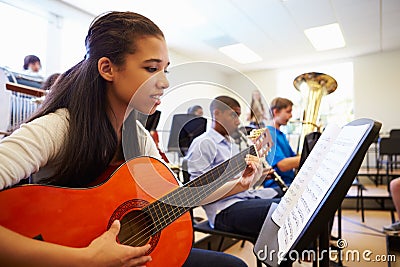 Female Pupil Playing Guitar In High School Orchestra Stock Photo