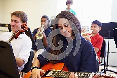Female Pupil Playing Guitar In High School Orchestra Stock Photo