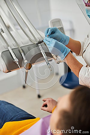 Female putting prophy paste on handpiece with polishing brush Stock Photo