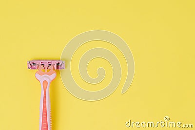 Female razor for depilation on a yellow background. Pink disposable razor. Top view, copy space Stock Photo