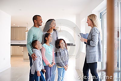 Female Realtor Showing Family Interested In Buying Around House Stock Photo