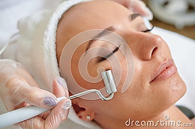 Female receiving electric facial treatment by cosmetologist wearing gloves professional services Stock Photo