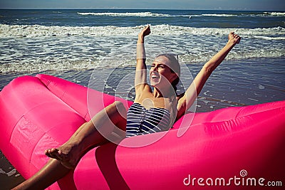 A female rejoicing on a deep-rosy air rubber boat upping her han Stock Photo