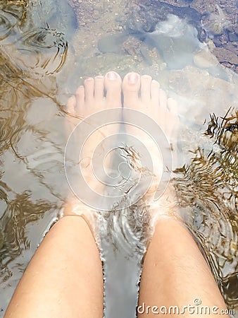 Female relaxing her feet in waterfall. Travel concept Stock Photo