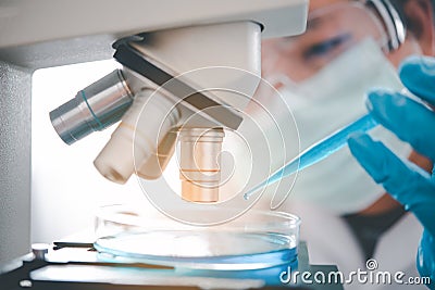 Female researchers are experimenting with pipette dropping a sample into a test tube in an experiment research in laboratory Stock Photo