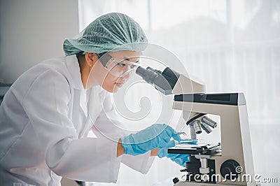 Female researchers are experimenting with pipette dropping a sample into a test tube in an experiment research in laboratory Stock Photo