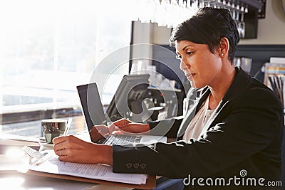 Female restaurant manager working at counter Stock Photo