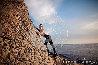 Female rock climber climbs on rocky wall Stock Photo