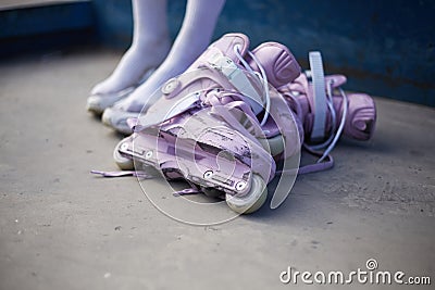 Female roller blader preparing for a ride in a skatepark. Young girl sitting in a urban park with a pair of modern purple Stock Photo