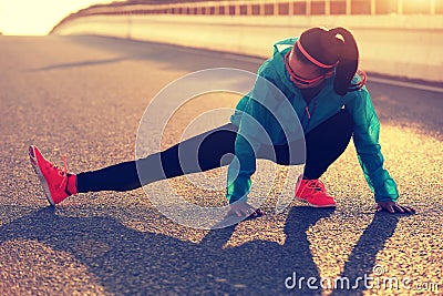 Female runner stretching her legs on sunrise road Stock Photo