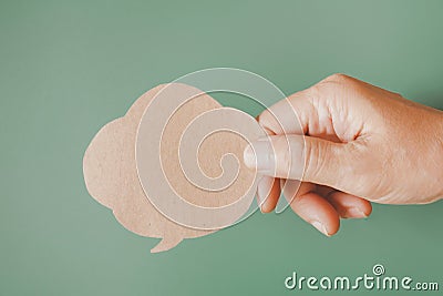 Female`s hand holding grunge brown bubble speech on dark green background Stock Photo