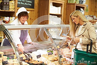 Female Sales Assistant Serving Customer In Delicatessen Stock Photo