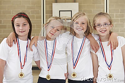 Female School Sports Team In Gym With Medals Stock Photo