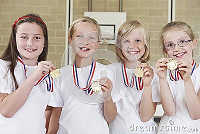 Female School Sports Team In Gym With Medals Stock Photo