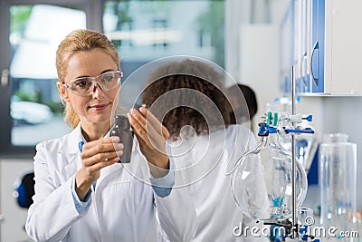 Female Scientific Researcher In Laboratory Doing Research, Woman Working With Chemicals Over Group Of Scientist Stock Photo