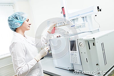 Female scientific researcher putting flask in Gas Chromatography Stock Photo