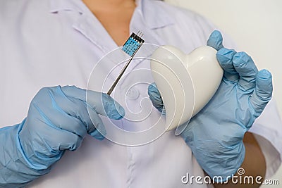 female scientist, doctor holding heart model, microprocessor, microchip, biochip tweezers for immunocytochemical studies heart, Stock Photo