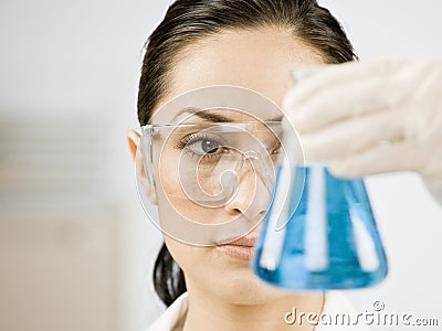 Female scientist looking at beaker of liquid Stock Photo