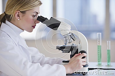 Female scientist looking through microscope Stock Photo