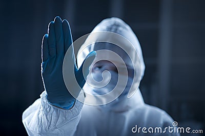 Female scientist in protective hazmat suit with hand raised Stock Photo