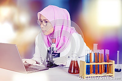 Female scientist using laptop and microscope Stock Photo