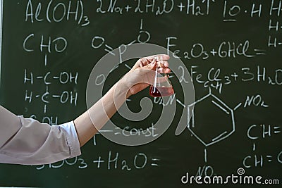 female scientist in white coat and glasses holding laboratory flask with red liquid Stock Photo