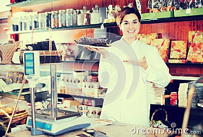 Female seller demonstrating delicious festive chocolate cake Stock Photo