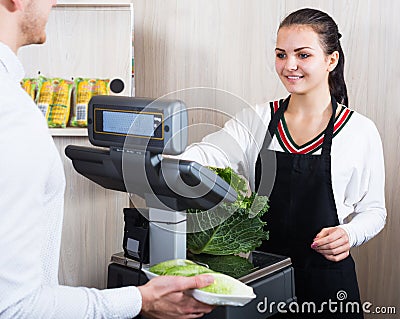 Female seller helping customer to weigh cabbage Stock Photo