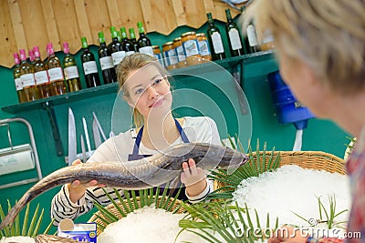 Female seller holding fish in front client Stock Photo