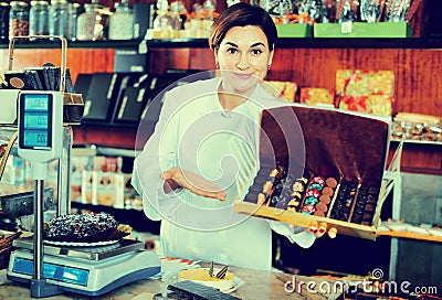 Female seller offering large box of chocolates Stock Photo