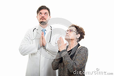 Female senior patient and male doctor praying together Stock Photo