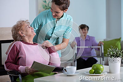 Senior residents in living room of nursing facility with supporting nurse Stock Photo