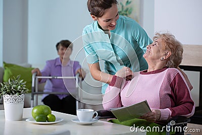 Senior residents in living room of nursing facility with supporting nurse Stock Photo