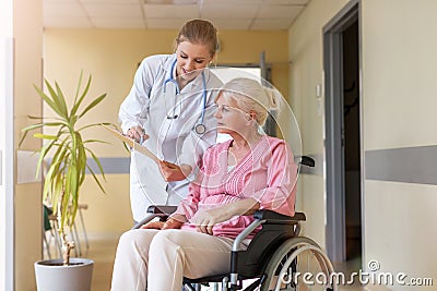Senior woman in wheelchair with nurse in hospital Stock Photo