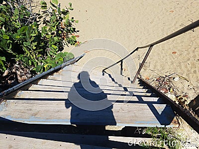 Female shadow on stairs to beach in Isabela, Puerto Rico Stock Photo