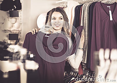 Female shopper examining long sleeve shirts in underwear shop Stock Photo